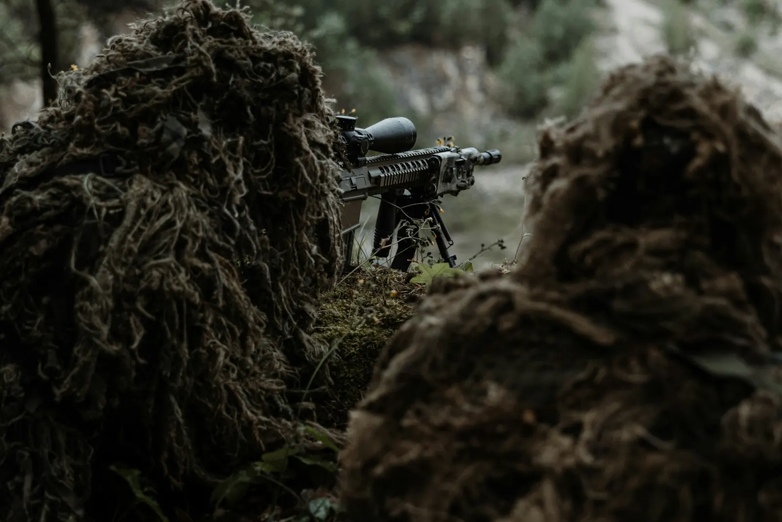 Deux snipers d'airsoft en tenue ghillie, en position de tir derrière une réplique à lunette montée sur bipied