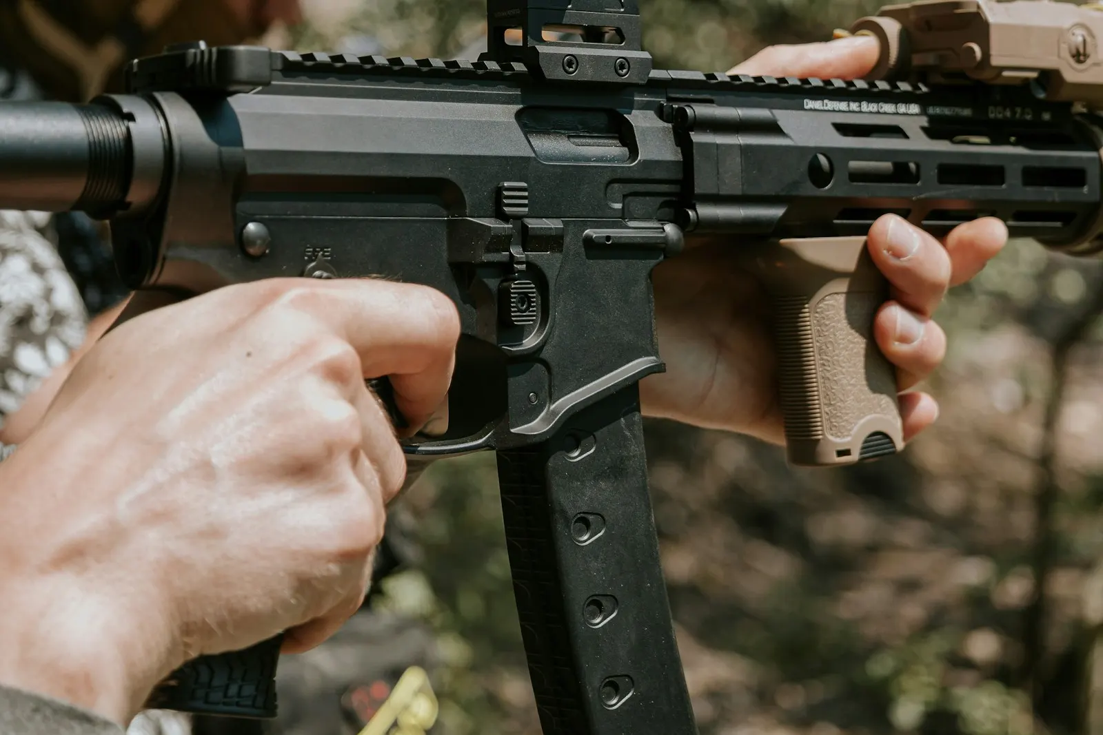 Joueur d'airsoft tenant une réplique électrique compacte équipée d'un viseur point rouge, doigt le long du pontet