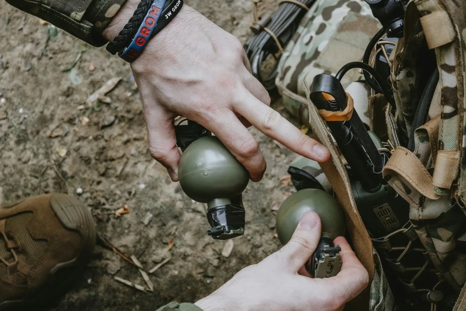 Joueur d'airsoft sortant deux grenades d'entraînement vertes d'une poche de son gilet